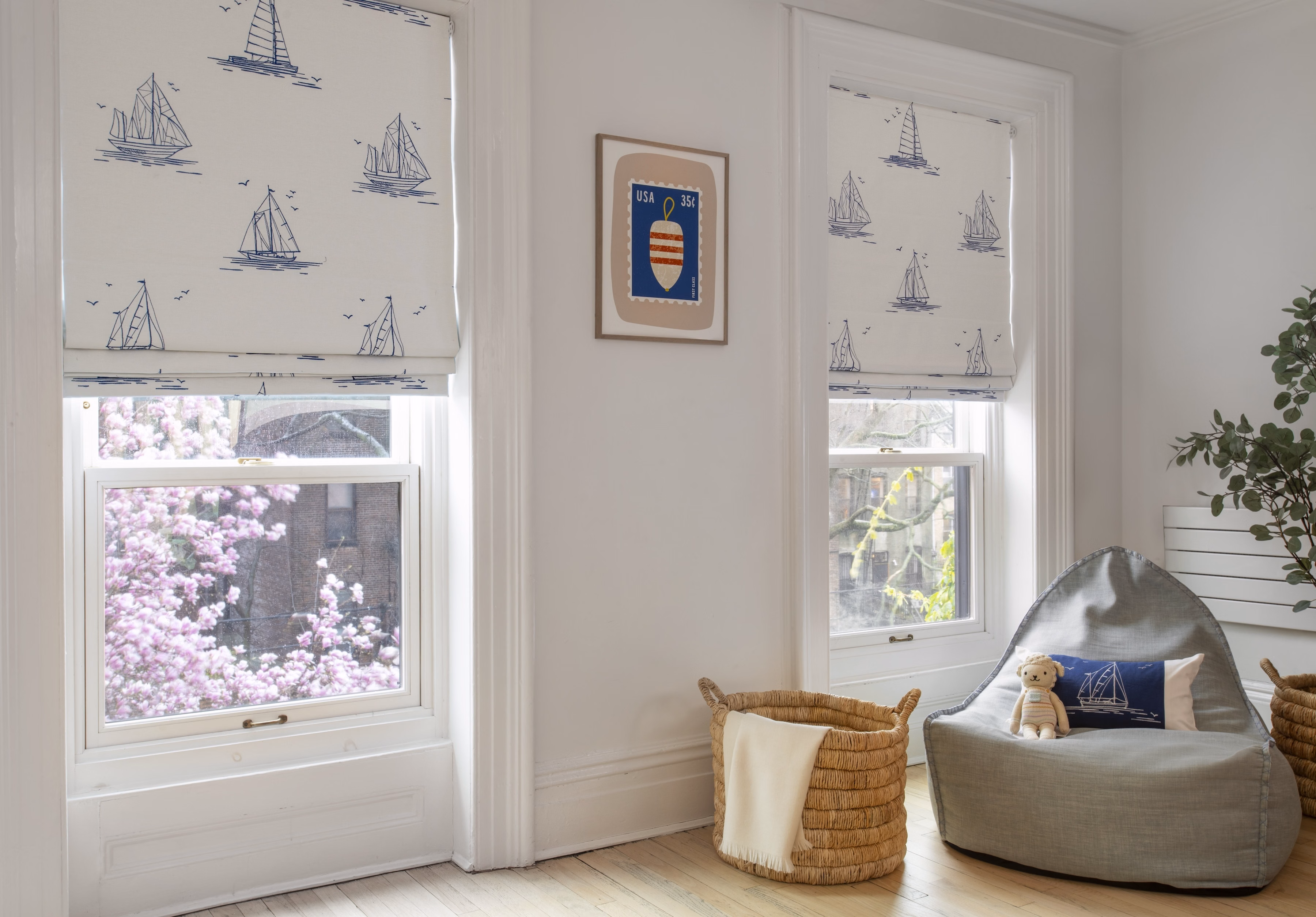 Sailboat-patterned blackout flat Roman shades add privacy and playful style to a bright children’s bedroom.