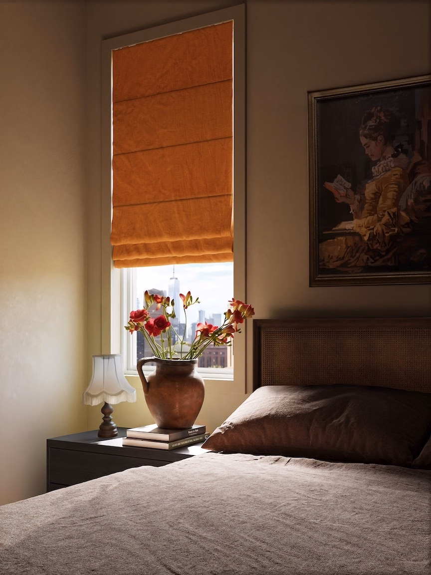 Sienna blackout linen pleated Roman shade adds warm color and privacy to a traditional bedroom window.