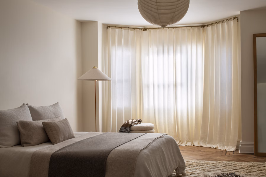 Custom curtain rods with decorative finials supporting drapery in a modern bedroom.