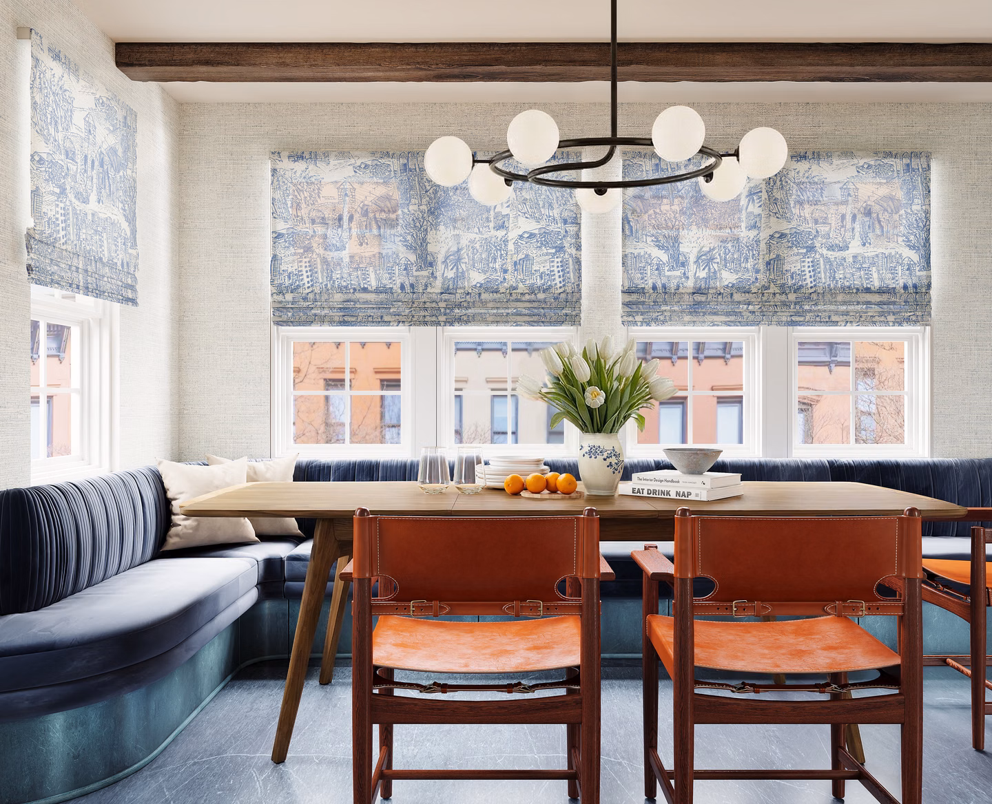 Patterned unlined flat Roman shades dress three dining nook windows above a built-in banquette.